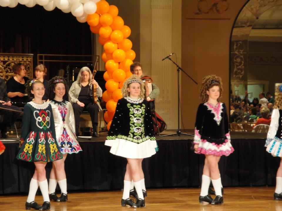 “Queen City Feis 2011” This is a solo dress, which is a dress worn by a dancer after advancing to a certain level (it differs from school to school) or after receiving certain places at competitions. Many girls will rent or borrow their dress, because they get very expensive. Mine was borrowed from my cousin’s girlfriend who used to dance for McGing. This photo was taken at a feis, and though it’s hard to see, it shows the typical set up for a large feis. It takes place in a large area, such as a gym or convention center, and has stages set up around the room. The stages are made of plywood and has a curtain erected at the back to enable the judges, who sit at a table in front of the stage, to see the dancers better. The dancers walk on in a line and take turns dancing in pairs. A musician sits to the side of the judge at one of the front corners of the stage. The judge writes down your numbers and takes notes as you dance. After the judge finishes for that group (for example, Hornpipe girls in the novice category for those under 16), they will post the top scores on a huge wall and you can get your individual score sheets with the comments on it.