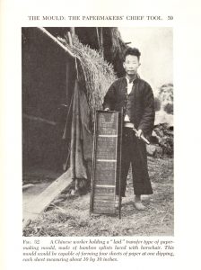 Black and white photograph of a Chinese man holding a paper making mold