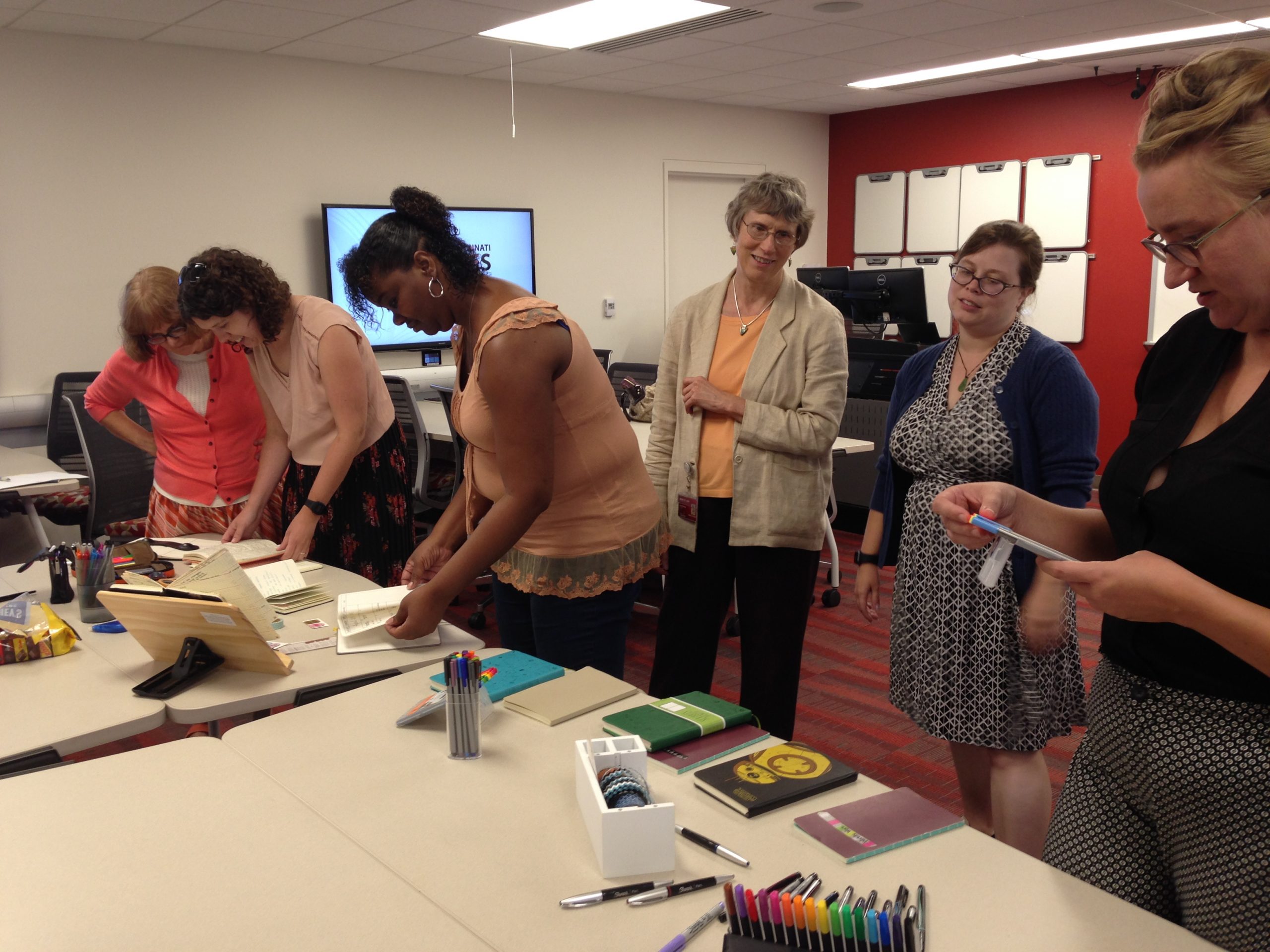 Workshop participants examining bullet journal supplies on table