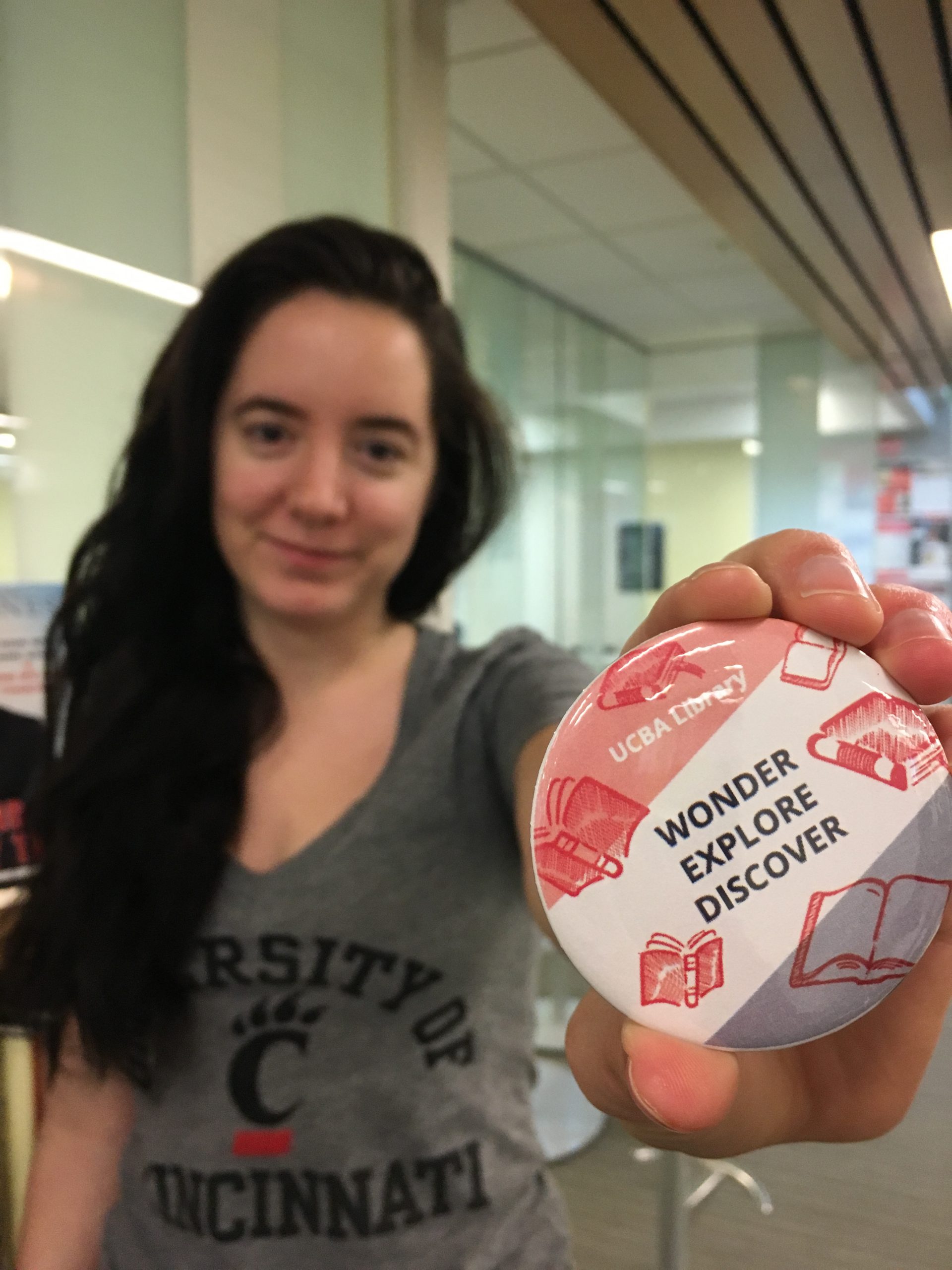 Student holding out their design winning button