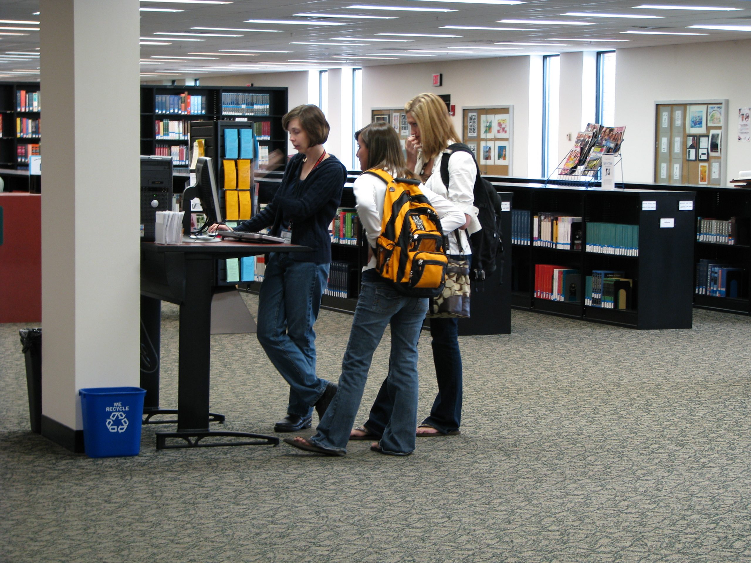 Lauren Wahman helping two students at stand-up computer station