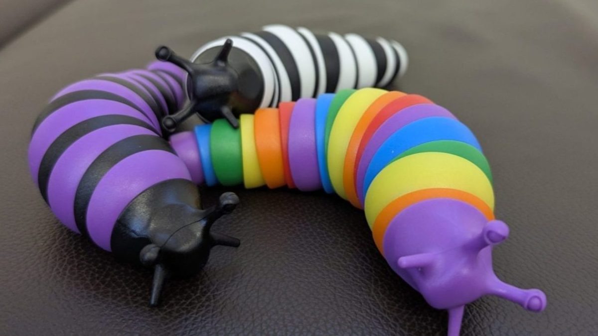 Three plastic, striped toy slugs. The left one is purple and black; the one in the back is black and white; the one on the right is rainbow.