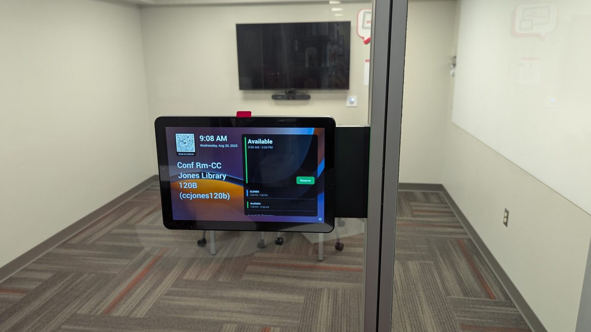 Tap display screen on a glass window with a TV/web cam in background