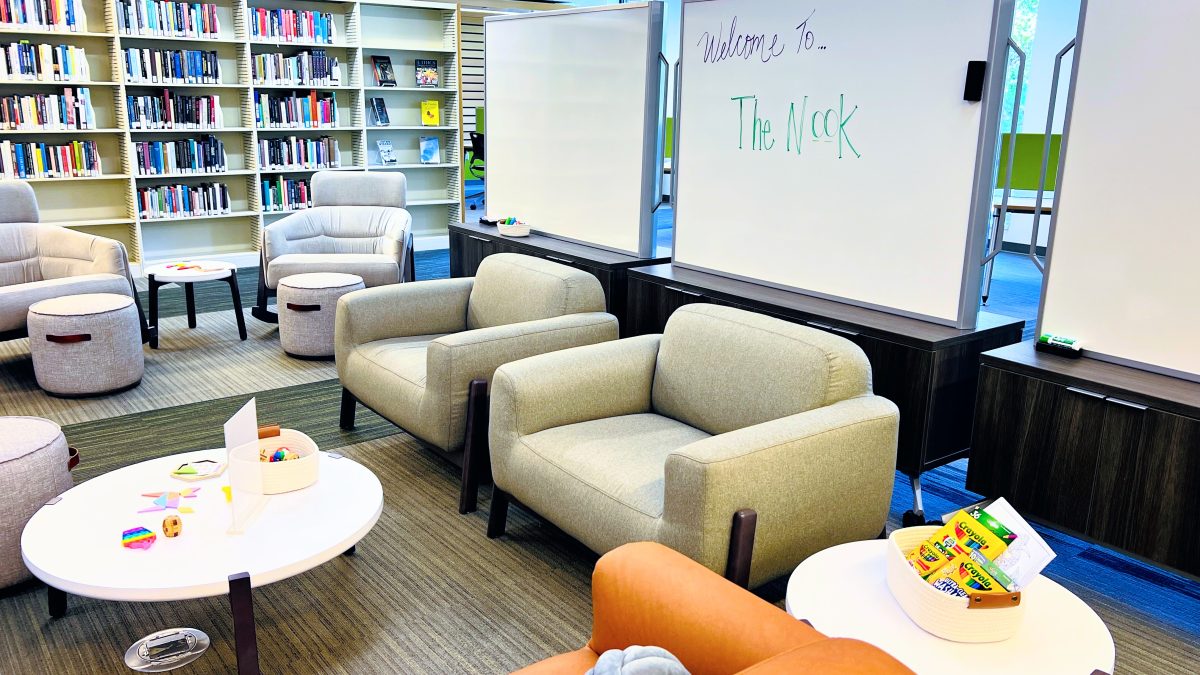 New Nook area filled with comfy seating and quiet activities like fidget spinners on tables. A handwritten sign saying Welcome to the Nook is shown on the whiteboard behind the furniture.