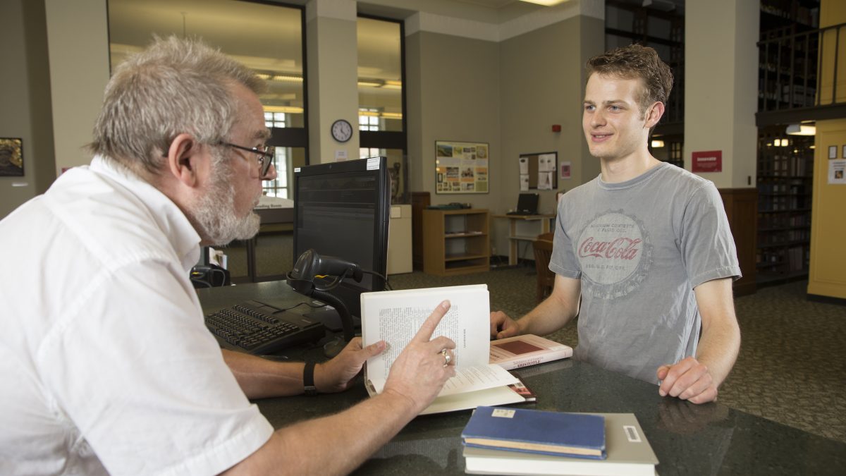 student talking with mike braunlin in the classics librry
