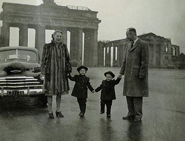 Photograph of Von Rosenstiel holding hands with his two children and wife in front of the destroyed Brandenburg Gate in Germany, 1947