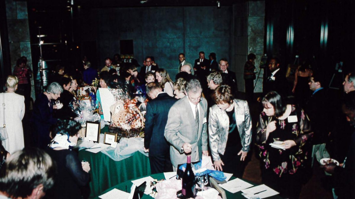 Individuals interacting at anniversary event around tables of food