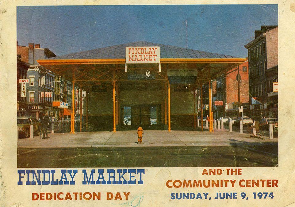 A color image from the front of the Findlay Market Dedication Day booklet in 1974 showing entry doors to Findlay Market and cars on the streets surrounding the market.