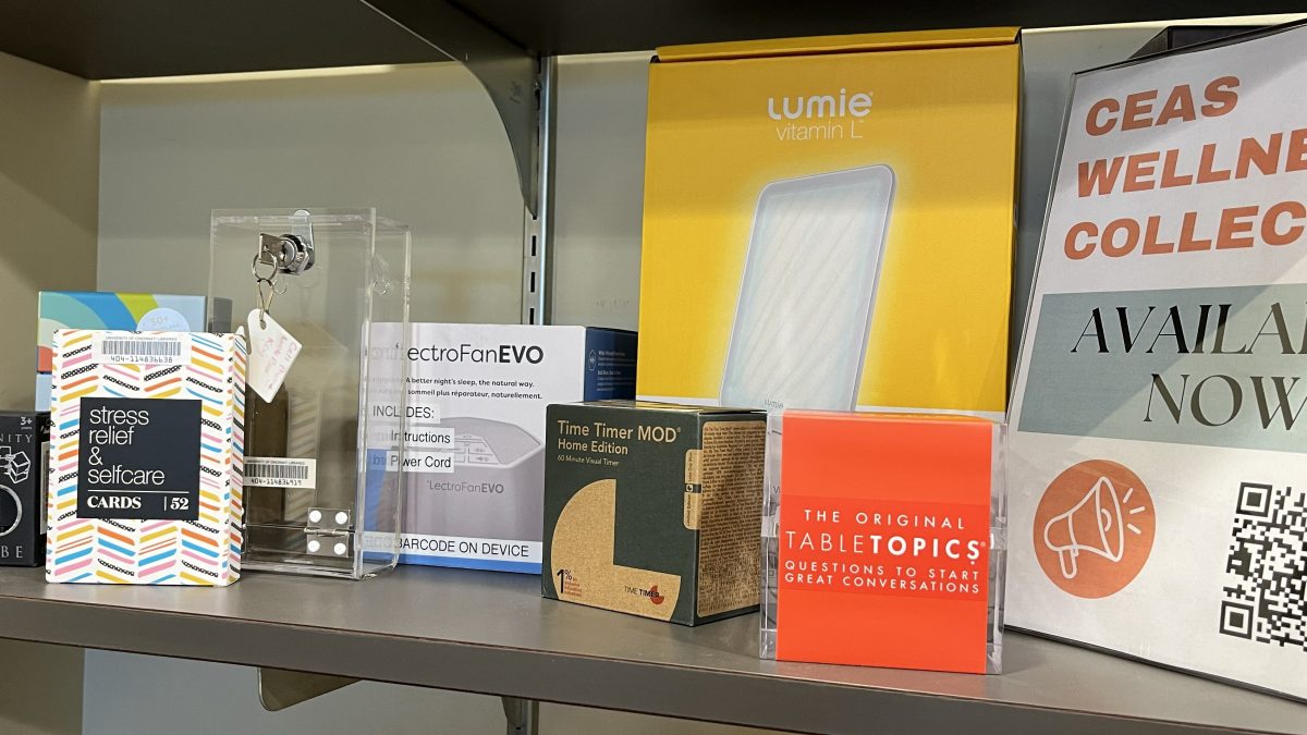 Shelf displaying wellness collection items including stress relief cards, phone lock box, vitamin L therapy lamp, timers, and table topics cards