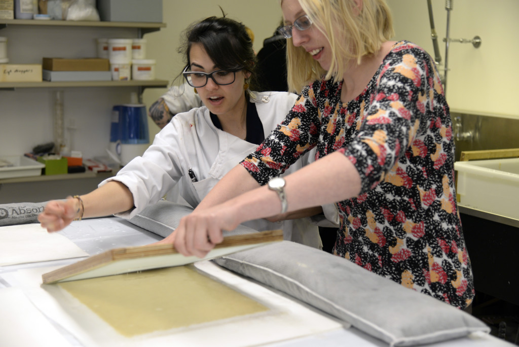 Catarina helping a visiting staff members couch her sheet of paper.