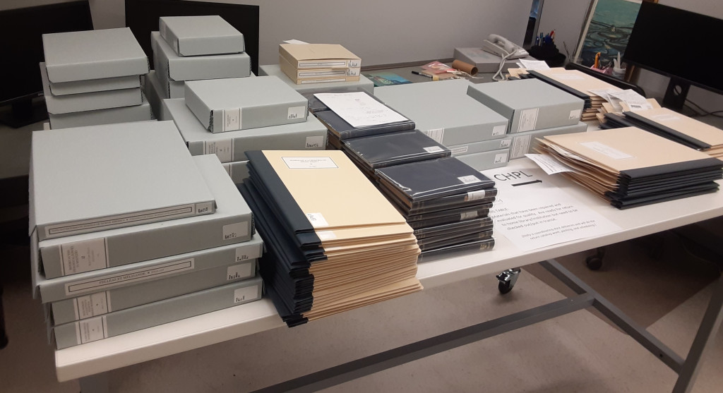 Books and pamphlets that have been repaired and housed organized on a white laboratory table. 