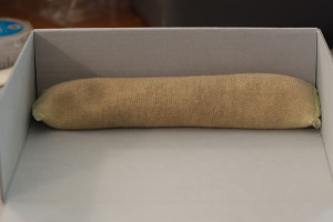 Weight nestled against enclosure wall to assist with adhesion of adhesive during drying.