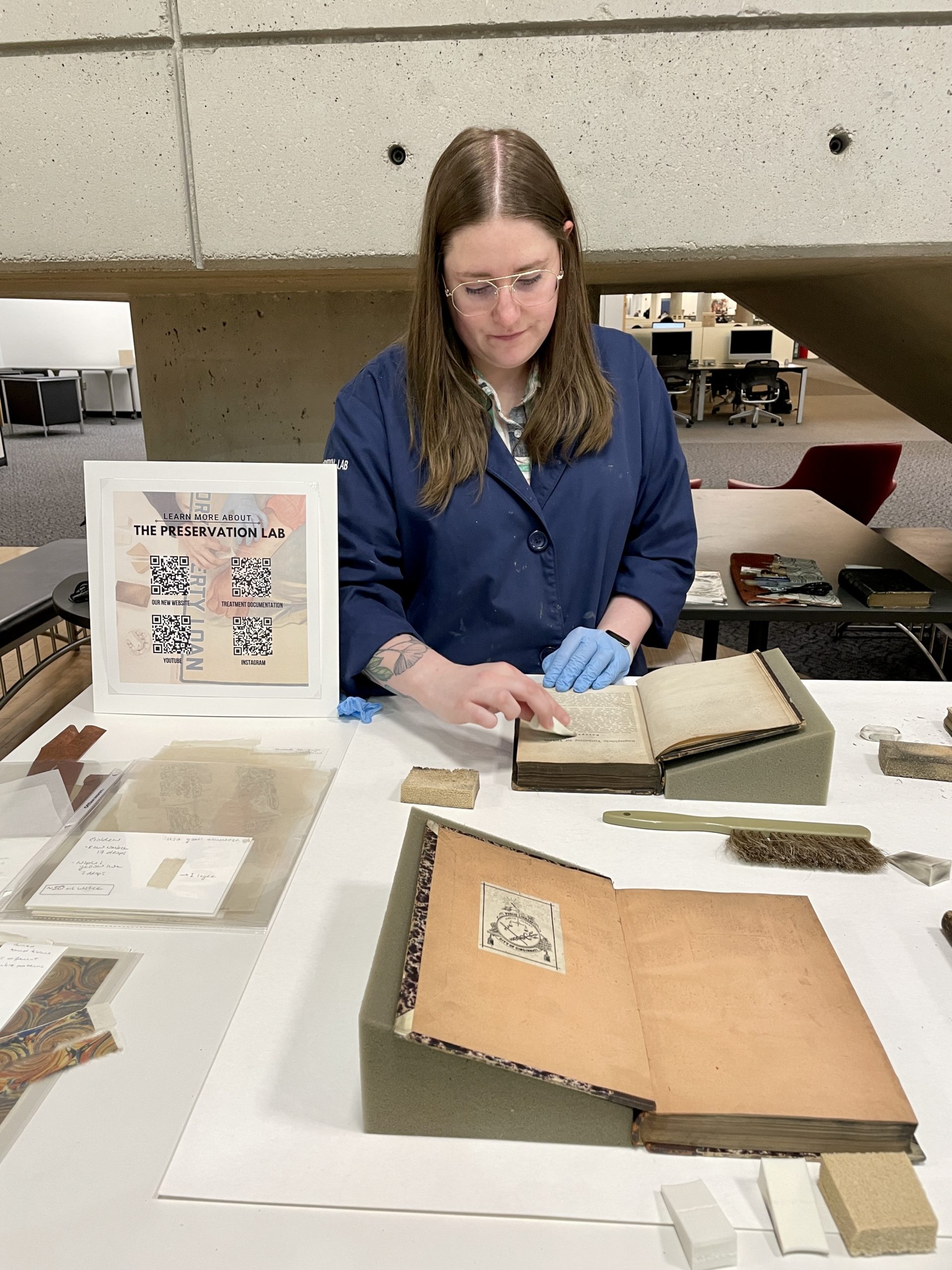 Jessica uses a sponge to clean soot off a book.