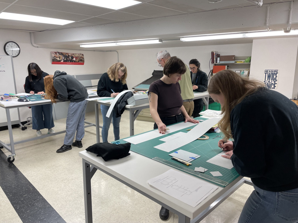 Students measuring and folding a tux box enclosure.