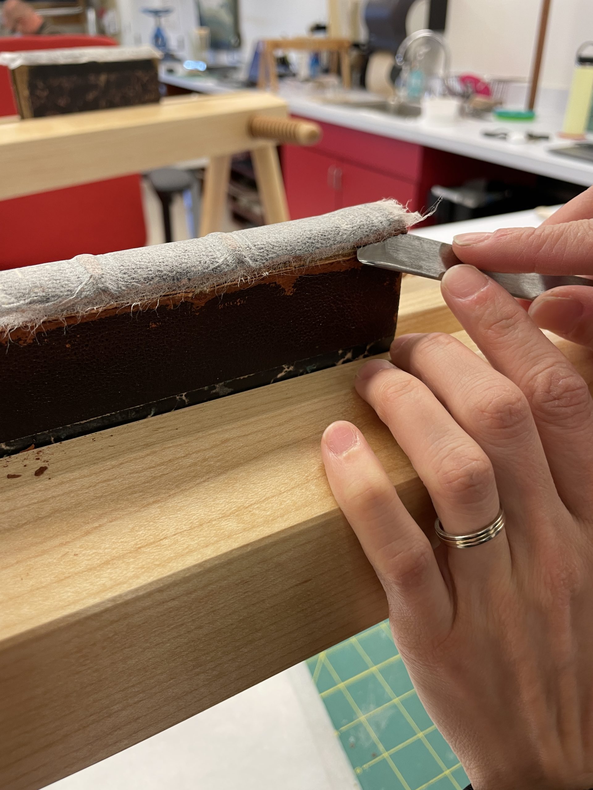 Book in press and the spine being removed with a lifting knife.