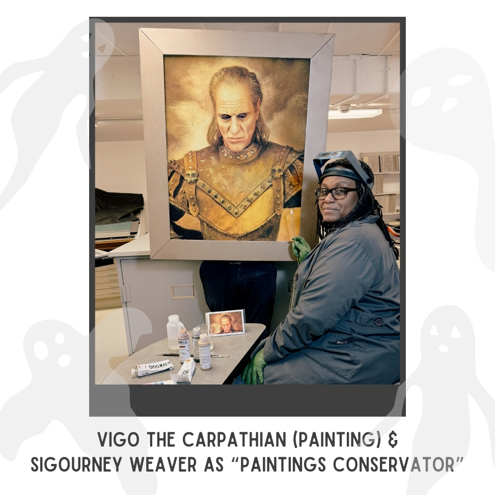 woman dressed as paintings conservator seated in front of a painting