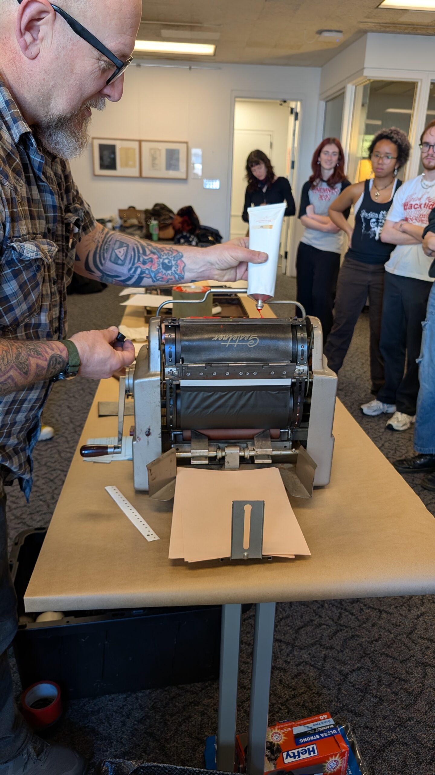 Image of Rich Dana putting in on the rollers of the mimeograph machine before printing.