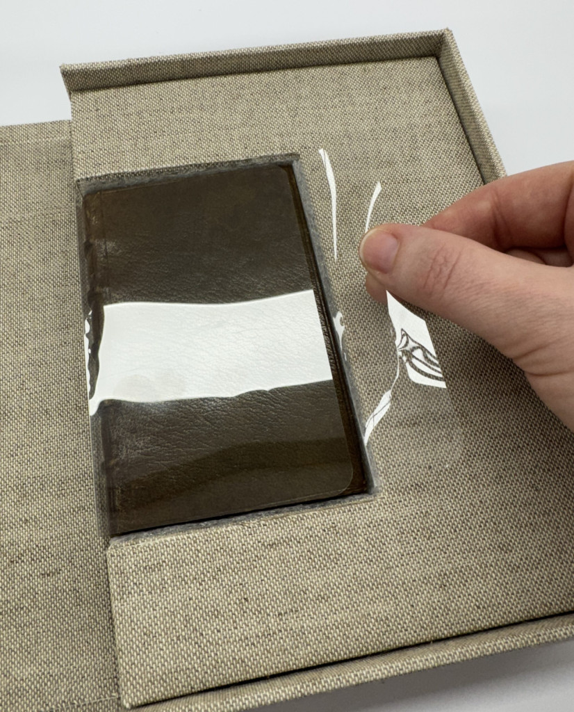 Small book in insert inside of custom box. Book is wrapped in a custom polyester wrapper.