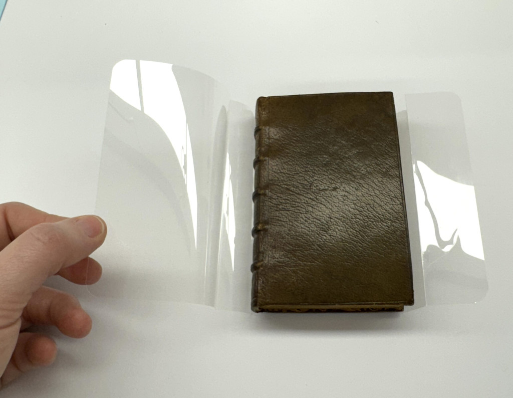 Book is wrapped in a custom polyester wrapper.