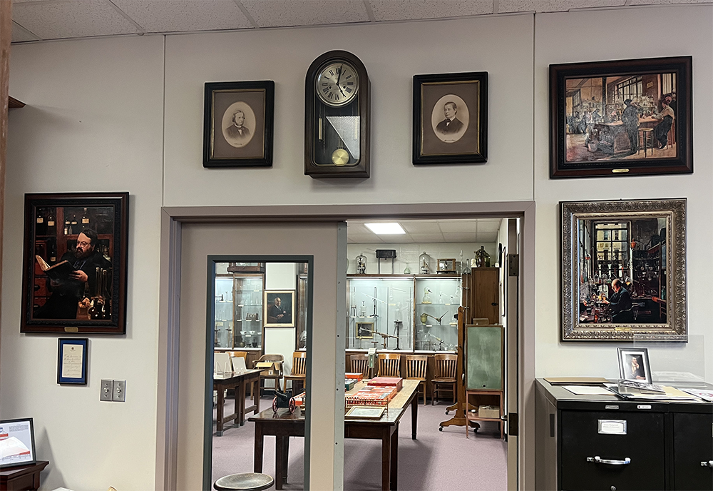 A collection of art on the wall of the Oesper collection library, with the two framed photographs hung over a doorway.