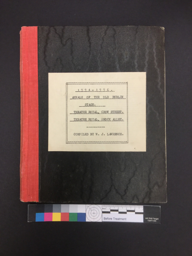 Overhead of a notebook with a black cover and red spine.