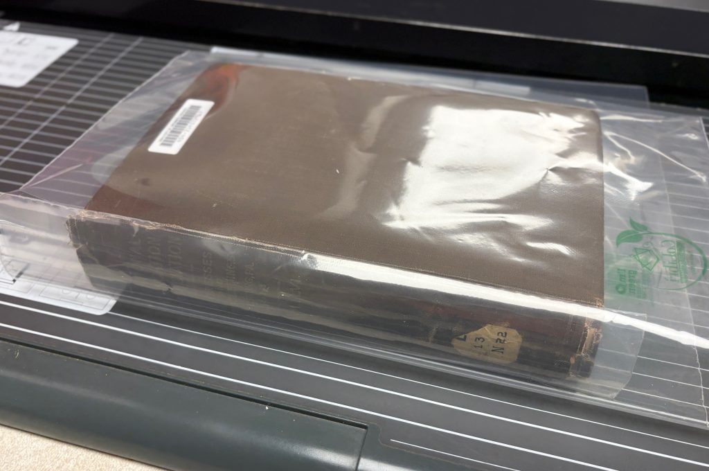 Book is closed with the jacket wrapped around the book.  The encapsulated spine pocket is loosely in place at the spine.