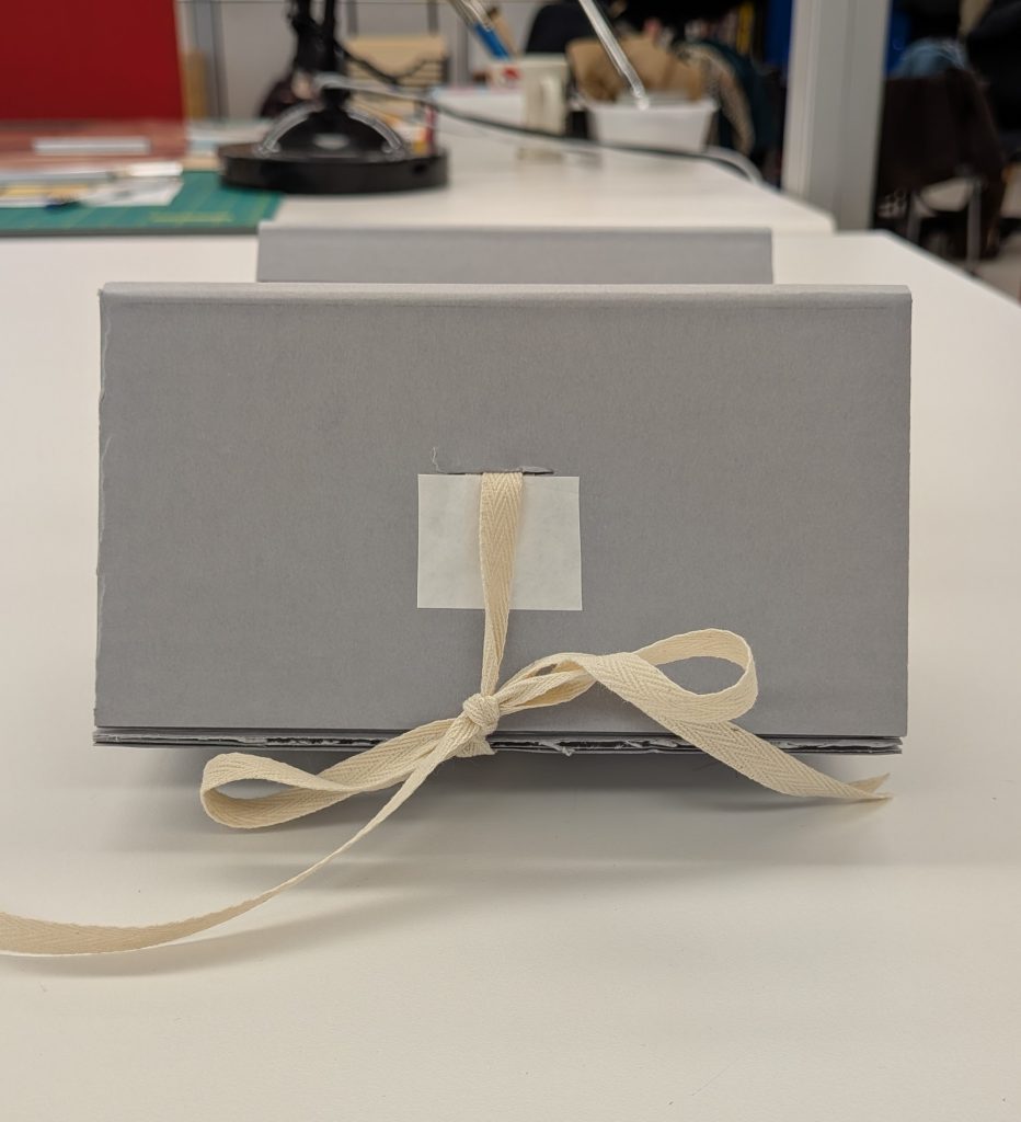 Corrugated cradle with cloth ties laced through it to tie and keep the cradle open.