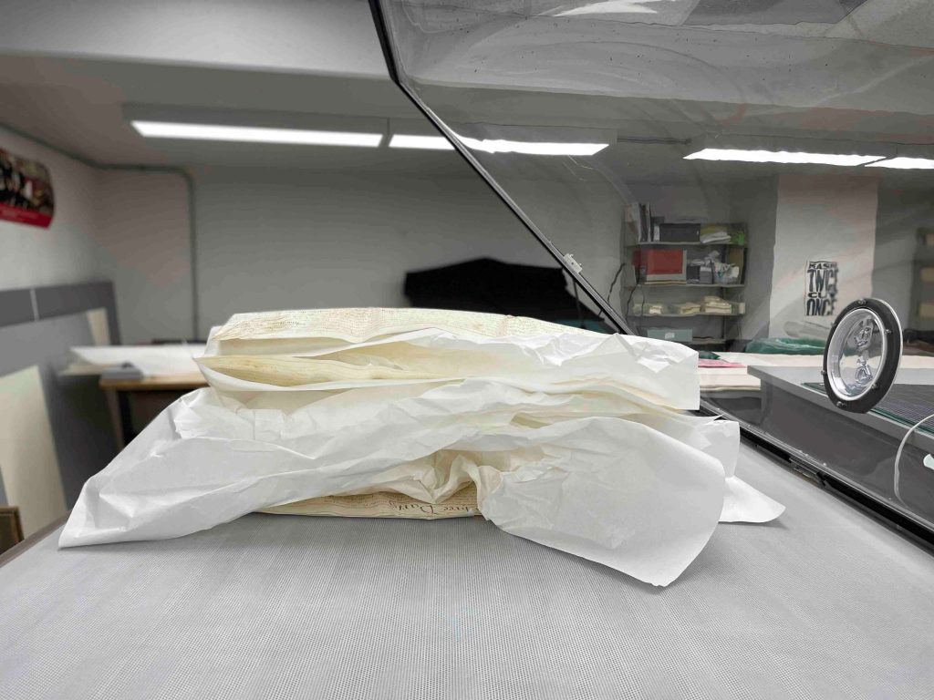 View of the three leaf parchment document, supported by interleaving to allow for air flow during humidification. 