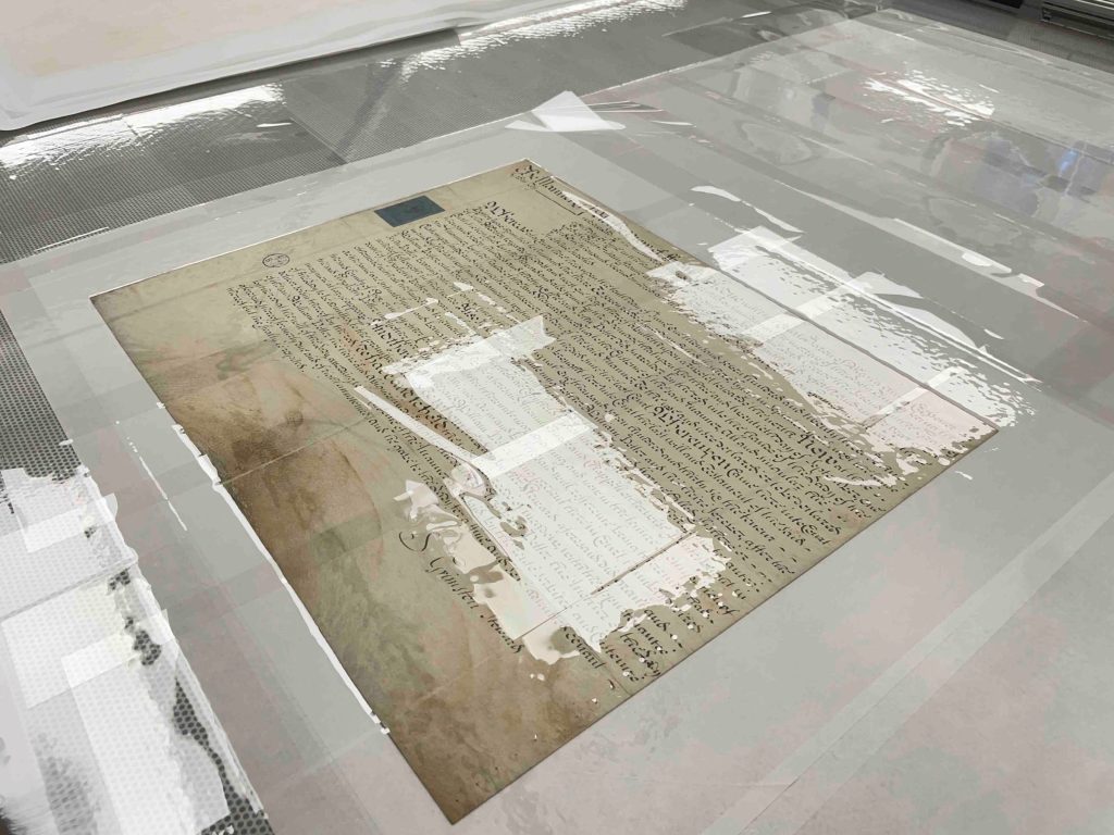 Parchment document under suction on a suction table.
