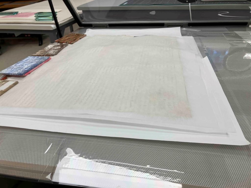 Parchment document under holly-tex, blotter and weights.