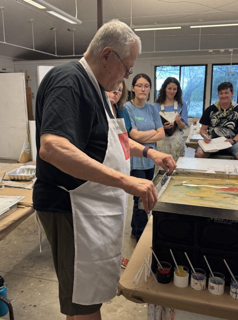 Instructor demoing at a marbling tray to a class full of students.