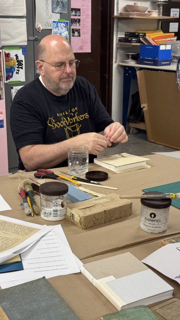 Todd adding wheat starch paste to the ends of the cords in preparation for lacing.