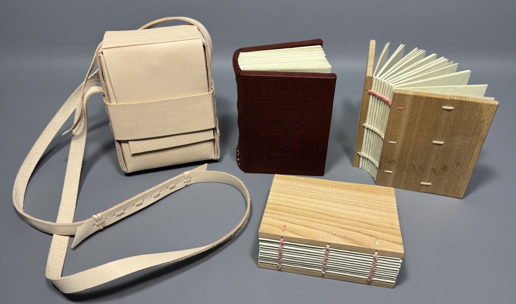 Four Ethiopian book models: one in a leather satchel, one covered in a dark red leather and blind tooled, and two with wooden boards and exposed sewing.