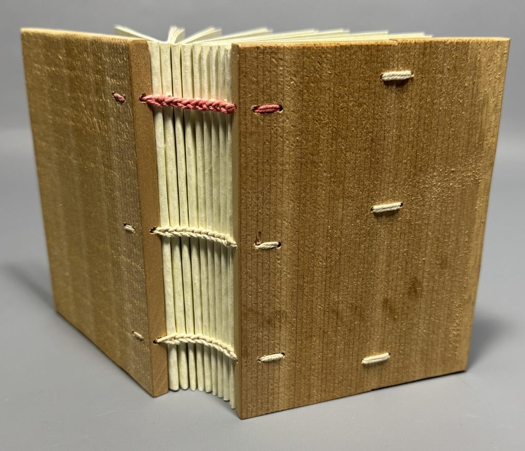 Book model with exposed sewing and wooden boards.