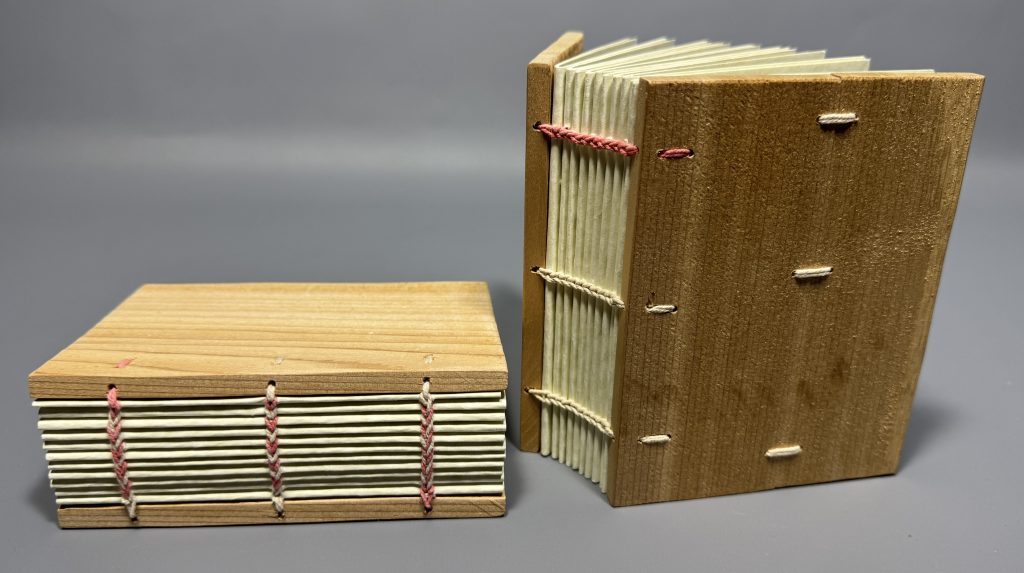 Two additional models with 3 station sewing, using dark pink thread to show how the pattern works. One book has a broken board that has been mended with thread.