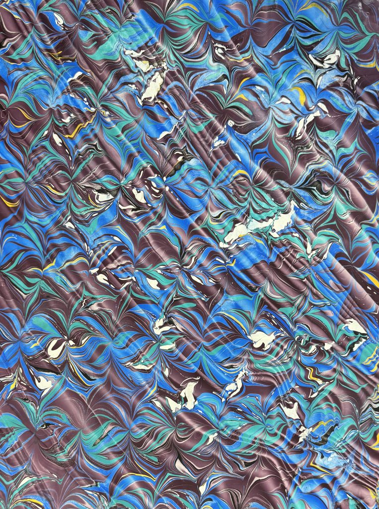 Nonpareil with Moire Spanish wave in shades of blue, mauve, yellow, green, black, and white.