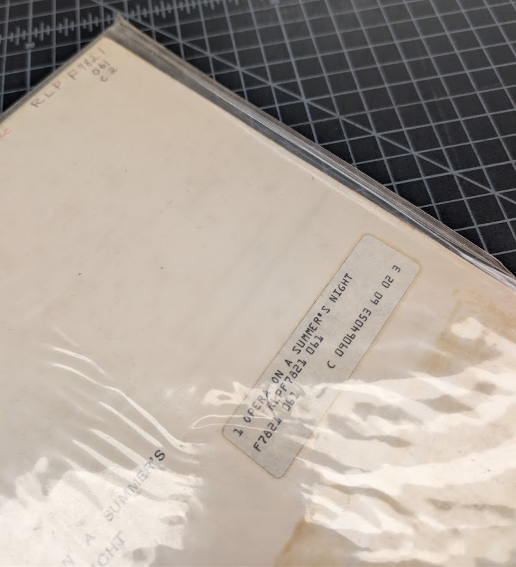 A plastic album sleeve that is curling around the edges.
