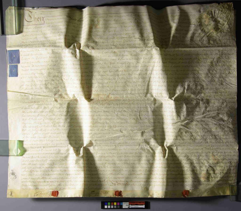 Overhead view of a parchment deed with three wax seals, with light source casting shadows over the document to show the folds.