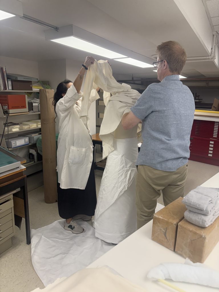 Nurse's uniform being placed over the head of the mannequin.