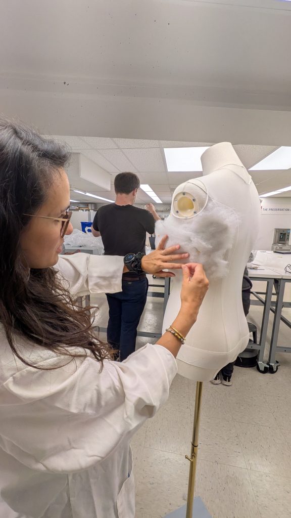 Conservator binning batting into place on mannequin bodice.