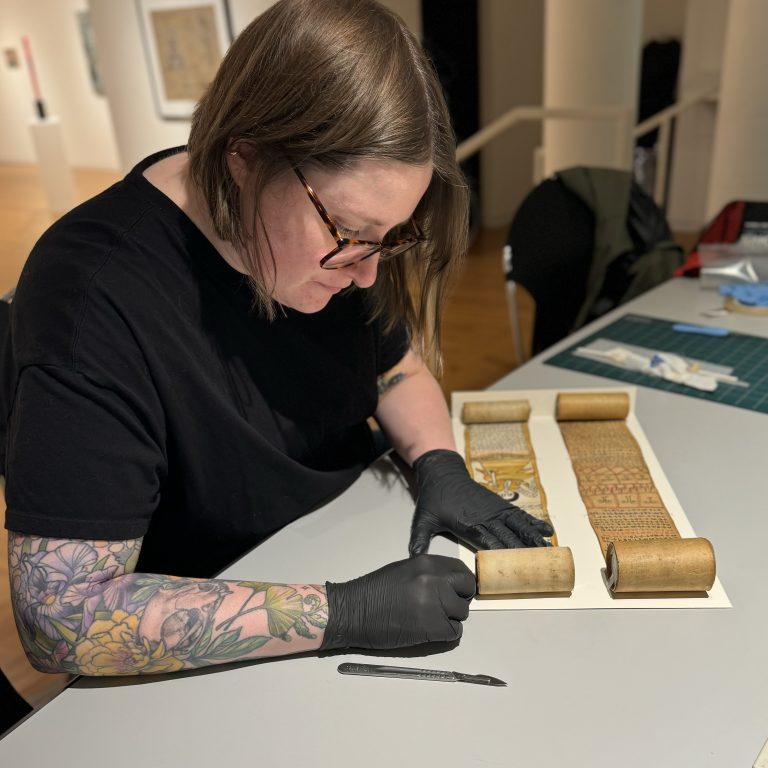 Conservator working on a rolled object.